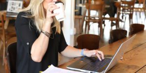 woman in a black shirt drinking coffee while working